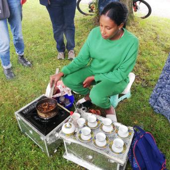 Azieb Waldematik aus Eritrea bei der traditionellen Kaffeezeremonie Bunn beim Einschenken von Kaffee aus einer Tonkanne (Jebena) in kleine Tassen.