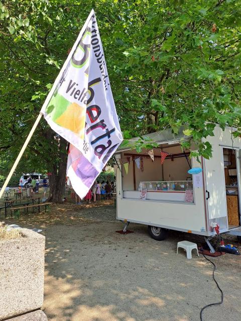 Ein mobiler Getränkewagen für unser Fest, davor weht die Fahne des Aktionsbündnisses.