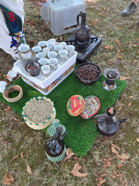 Traditionelles Zubehör für eine eritreische Kaffeezeremonie, ebenerdig auf dem Boden arrangiert mit kleinen Tassen, Kaffeebohnen, Zucker und Kaffeekannen.