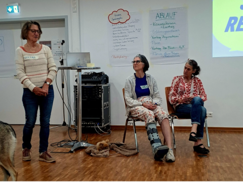 Frau Dr. Martha Cremer-Bach steht seitlich vor den Teilnehmerinnen und Teilnehmern um den Workshop einzuläuten.
